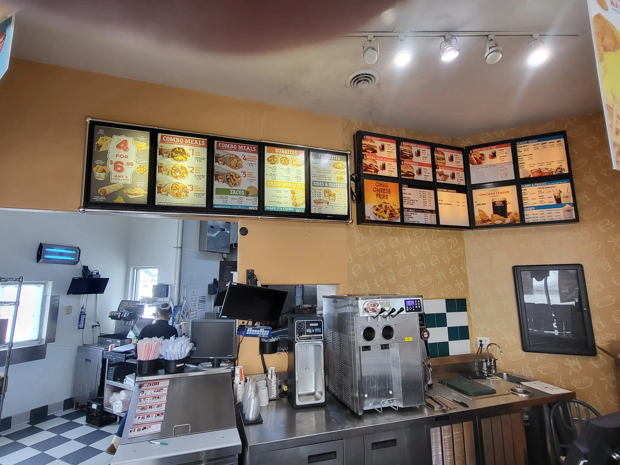 Backlit menu boards and ceiling track lighting above a restaurant service line