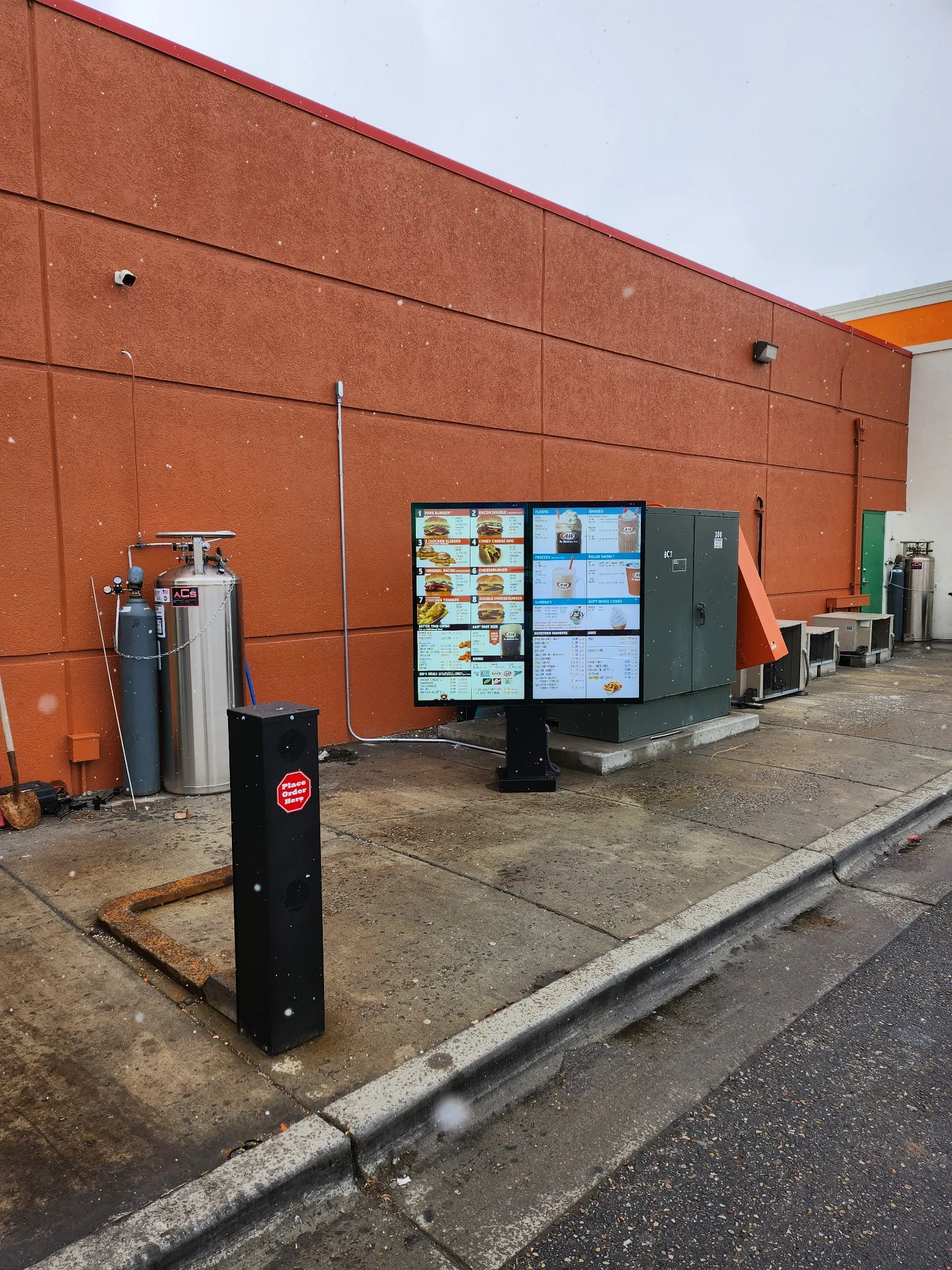 Completed drive-thru digital menu boards lit and running alongside a restaurant lane