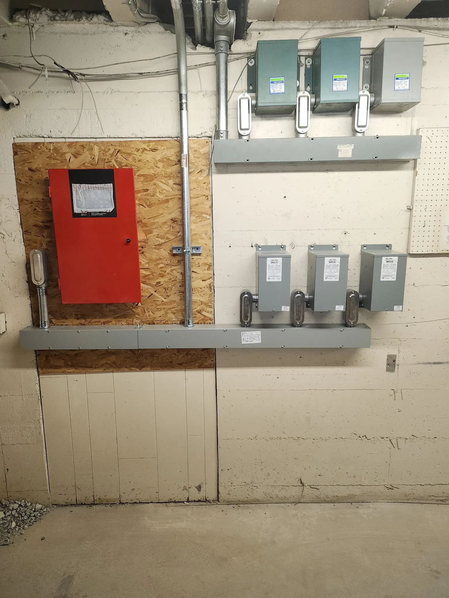 Bank of grey safety disconnect switches on a unistrut rack beside a red fire alarm panel