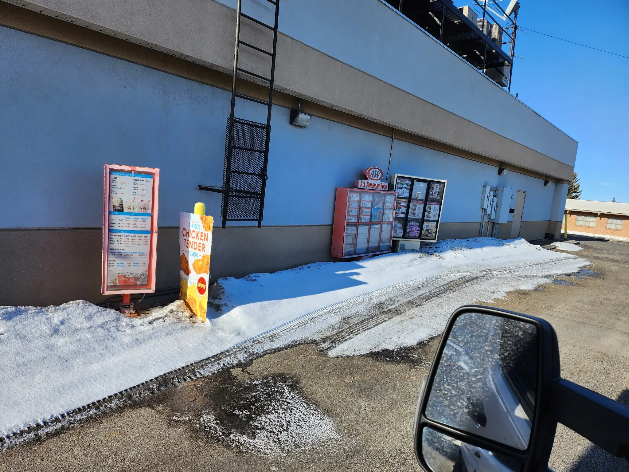 Exterior of a drive-thru restaurant with snow on the ground, seen from the service van