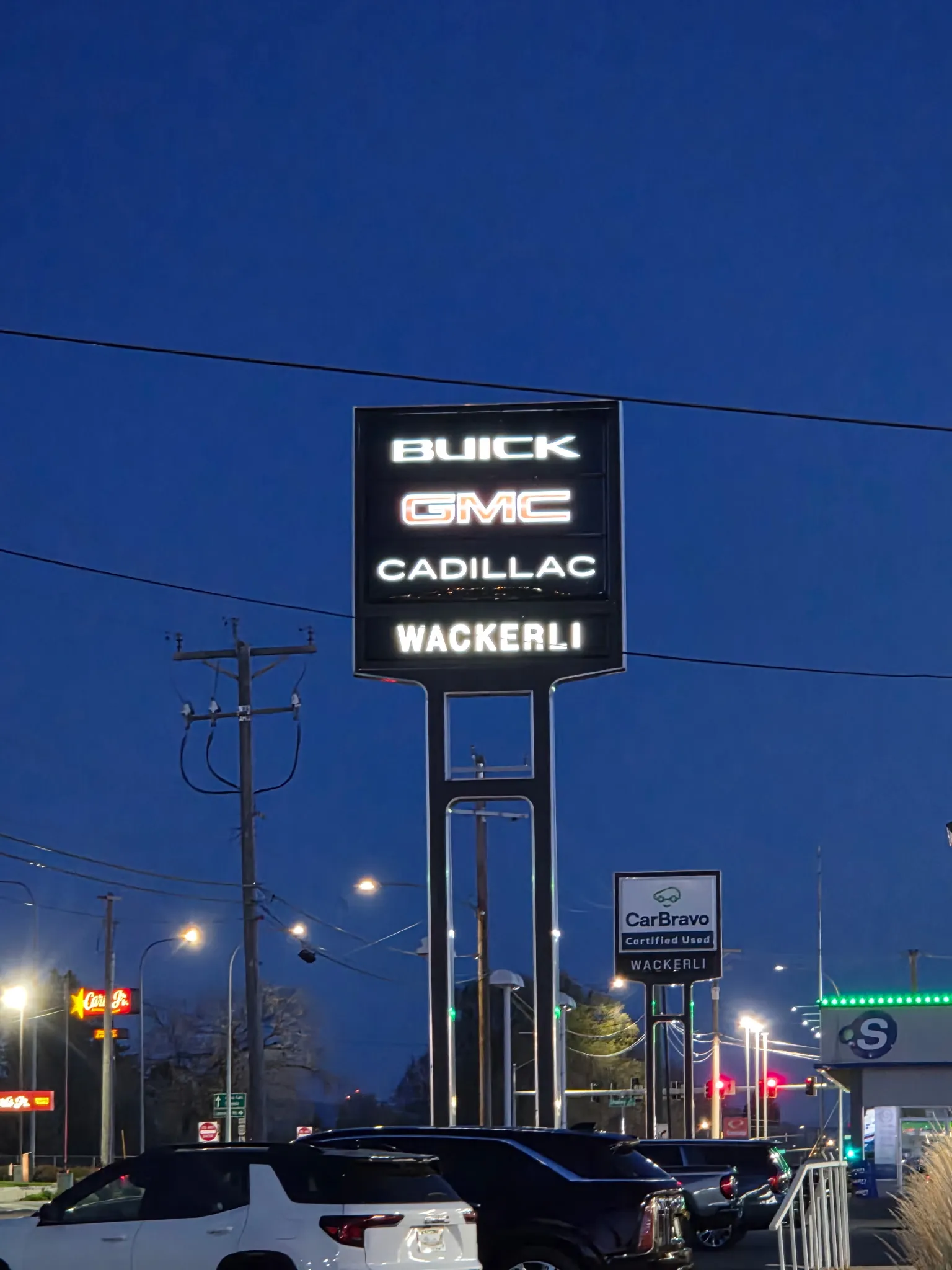 Tall illuminated dealership pylon sign lit against a deep blue dusk sky