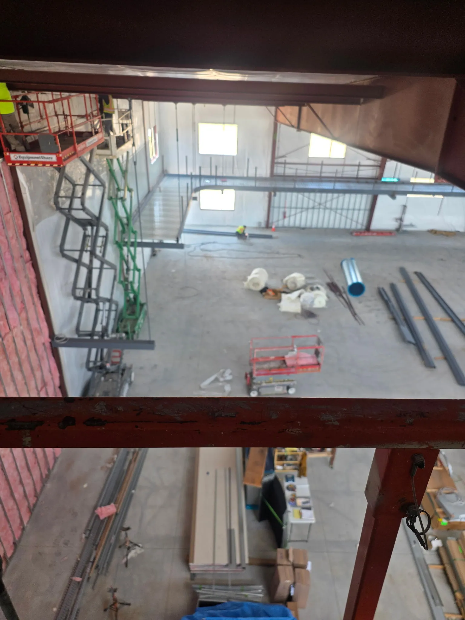 Interior of a commercial building under construction, exposed steel beams and a scissor lift