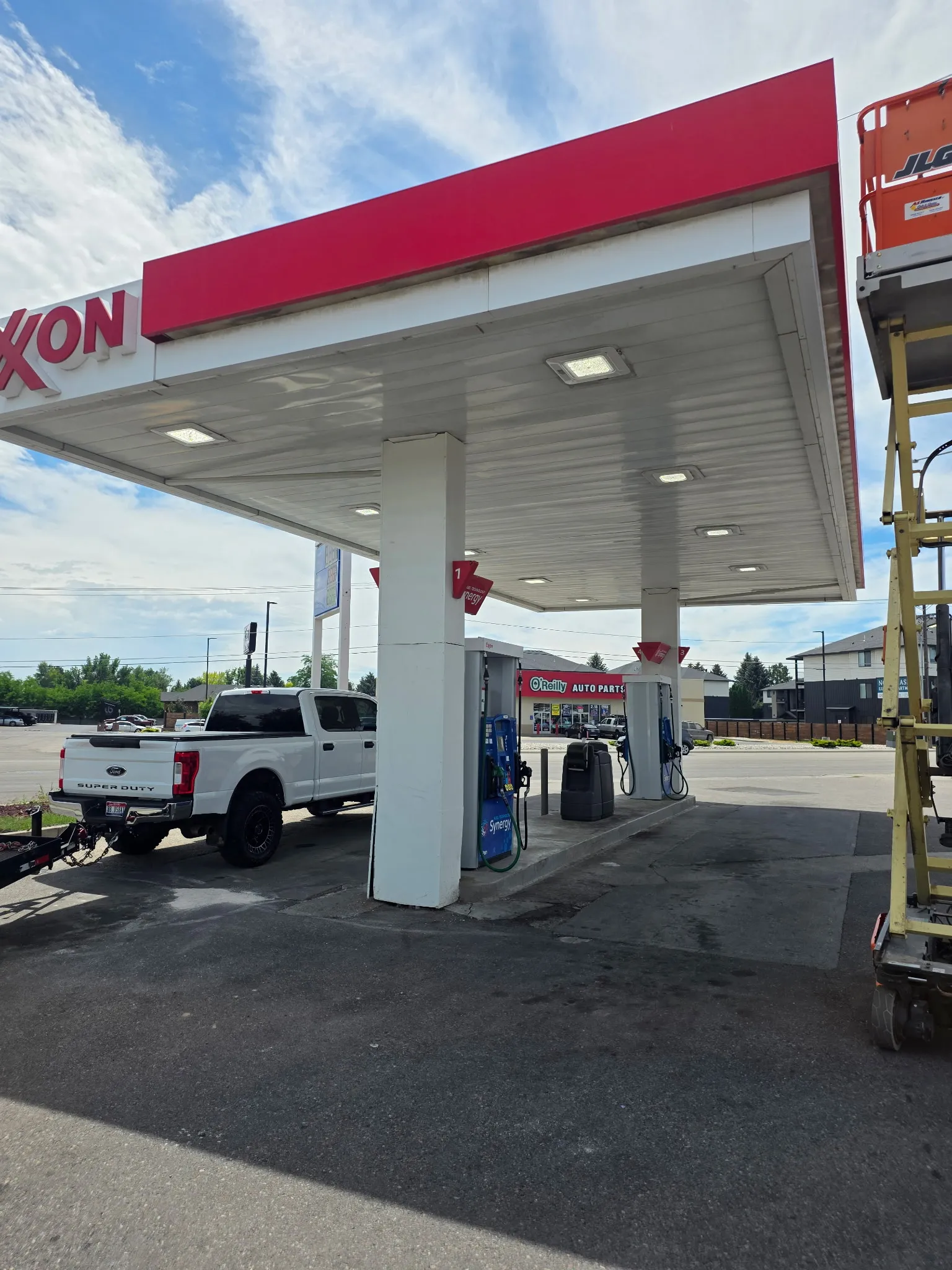 Fuel station forecourt with canopy lighting and a lift positioned for work